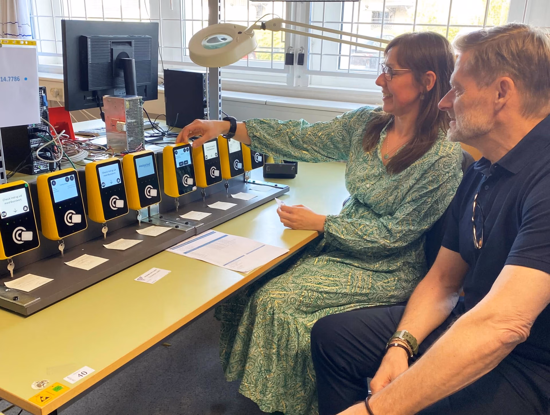 Two people testing yellow electronic payment terminals